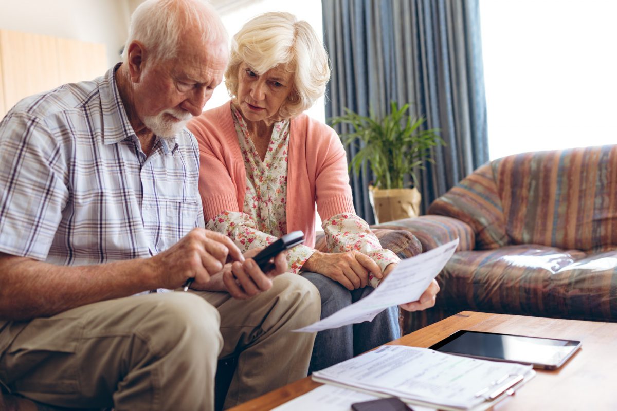 Front view of active Senior Caucasian couple calculating bill while sitting at retirement home
