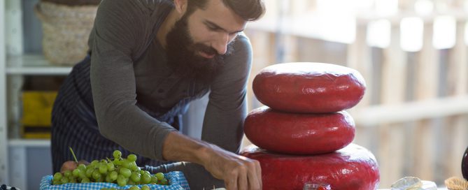 Salesman arranging cheese at counter